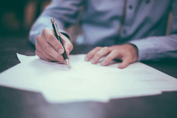 Man writing on a piece of paper while he works at home.