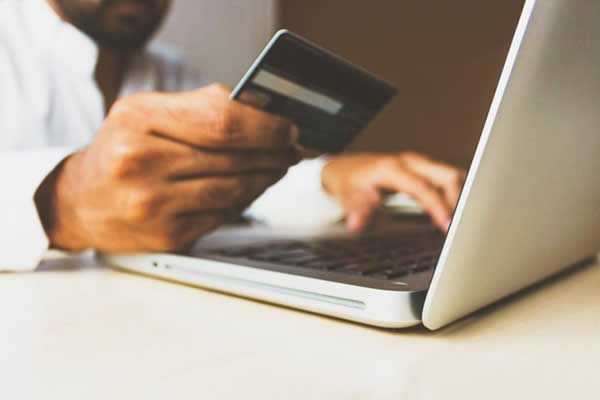 Man pulling out his credit card in front of his computer for online shopping. 