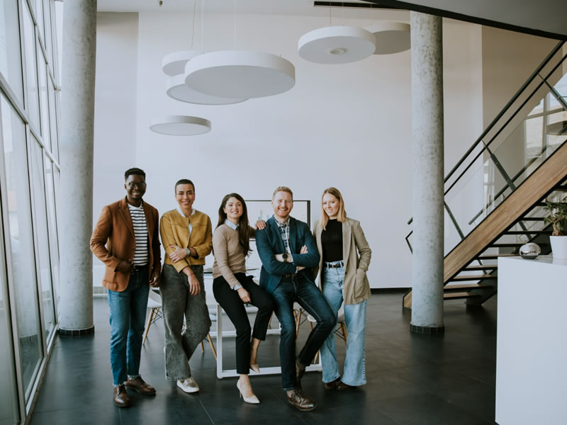 Five professional people posing for a photo in a room