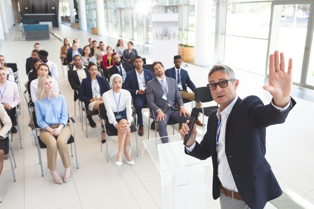 A professional speaker presenting in front of a group about the benefits of marketing for speakers Industries