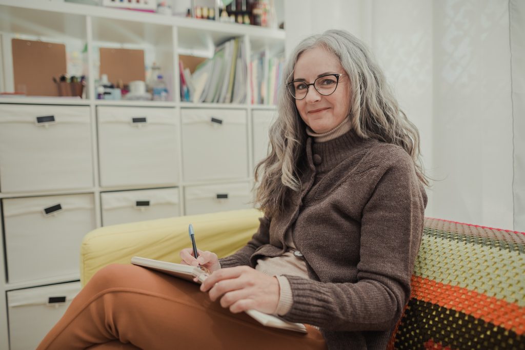 A woman with gray hair outside holding a notebook thinking about digital marketing for authors Indsutries